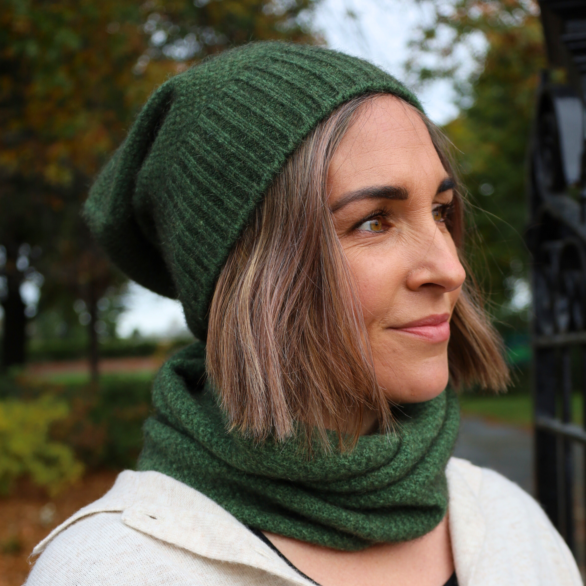 A woman wearing a black merino possum moss neck warmer in an outdoor setting.